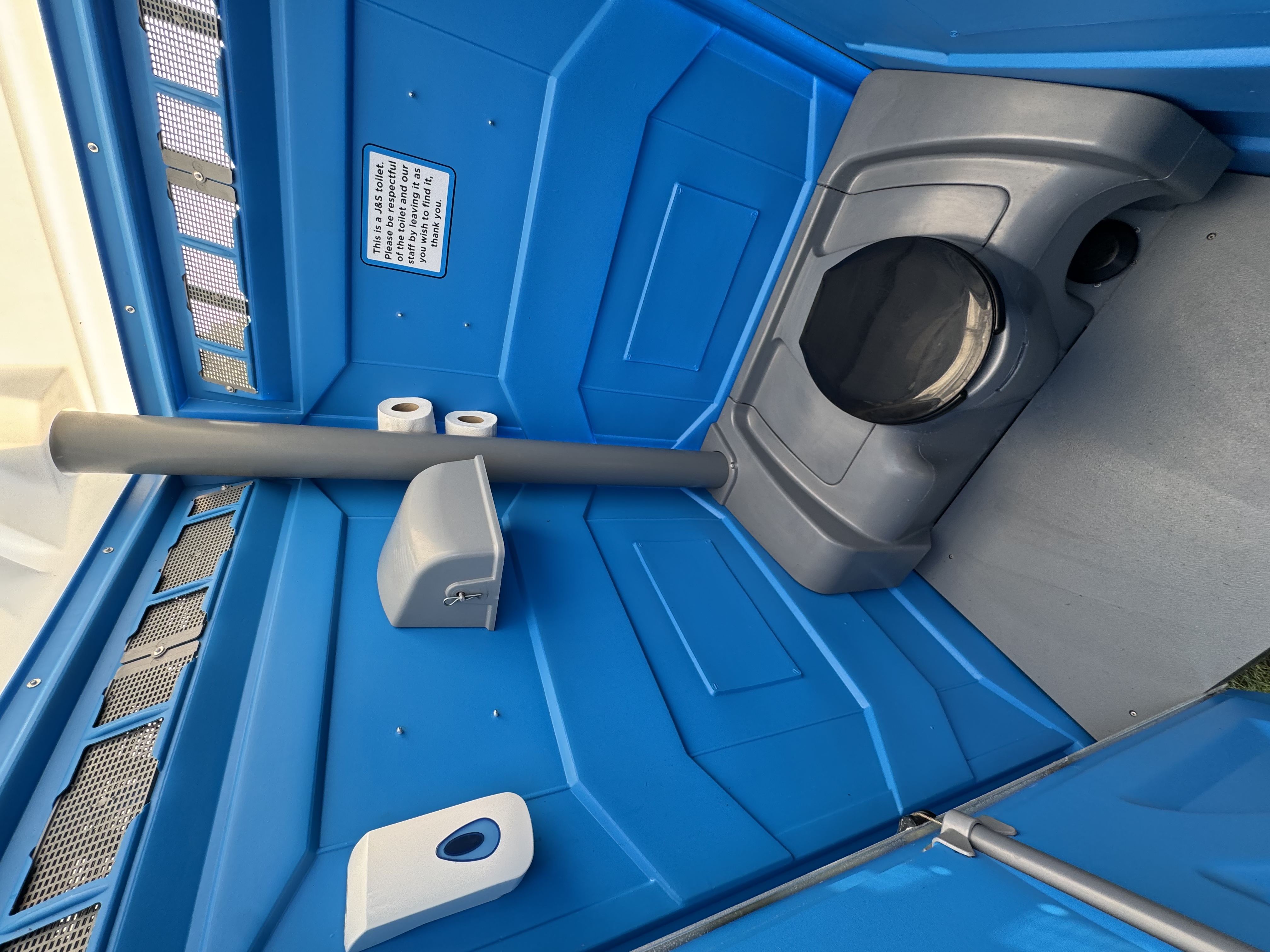 Interior view of event portable toilet showing facilities, hand sanitizer, and J&S Toilet Hire branding
