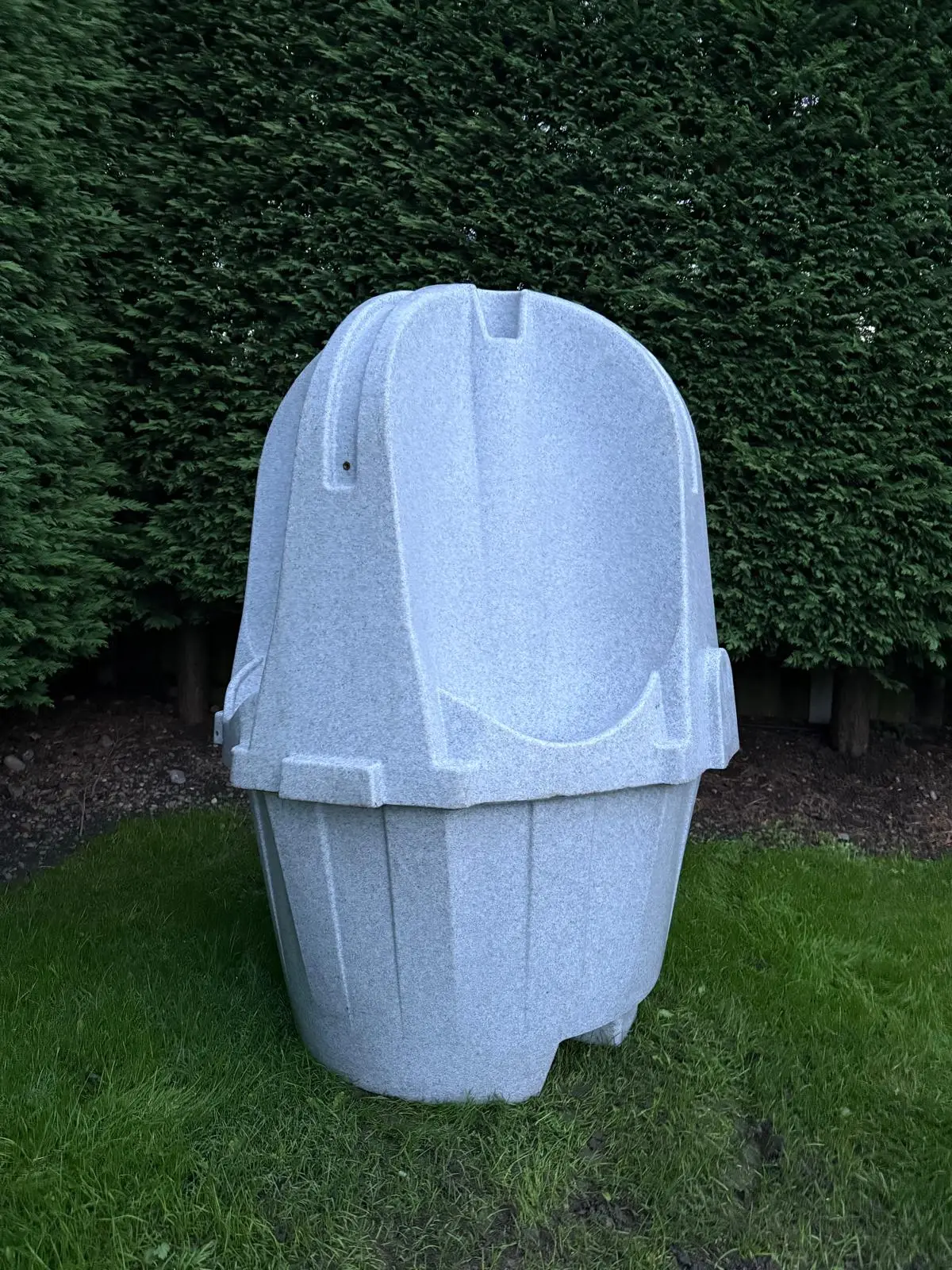 Full view of a single grey portable urinal unit on grass